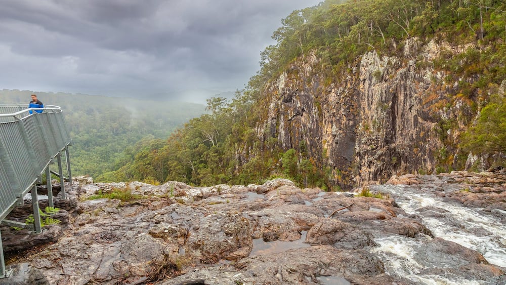 A rocky riverbed with a metal walkway and a person standing on it.