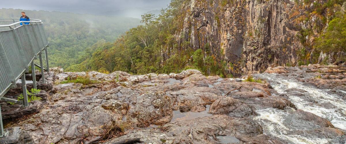 A rocky riverbed with a metal walkway and a person standing on it.