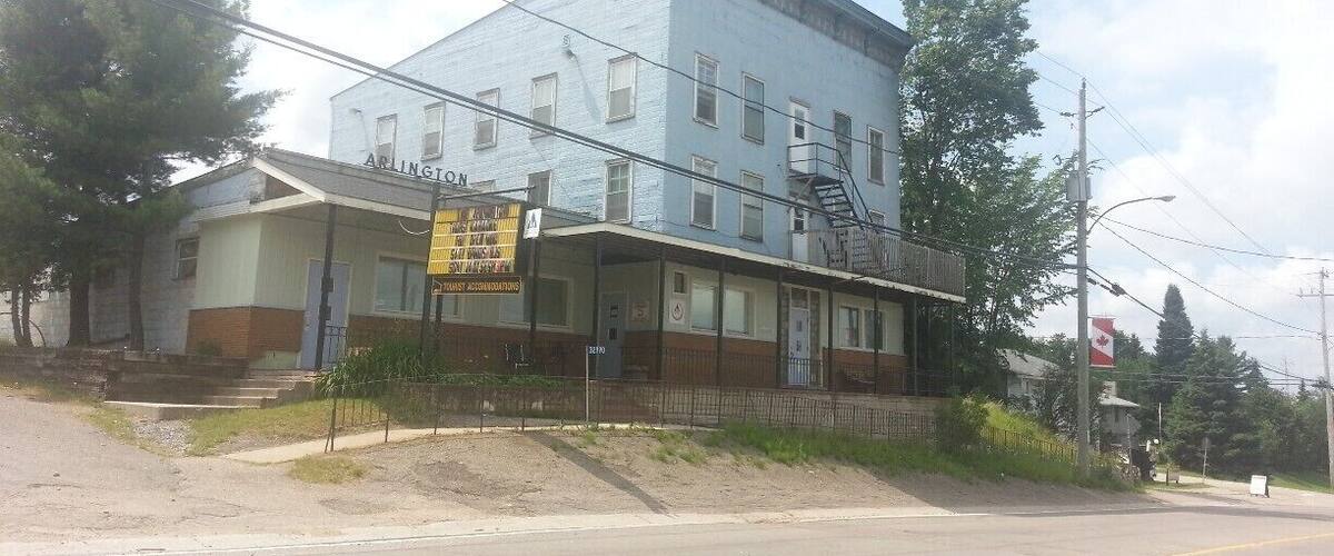 A two-story building with a sign reading "ARLINGTON" and a yellow sign advertising "STAY & DINE".