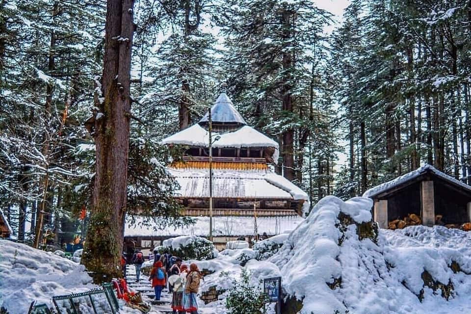 Un bosque cubierto de nieve con una estructura de madera tradicional y un edificio pequeño.