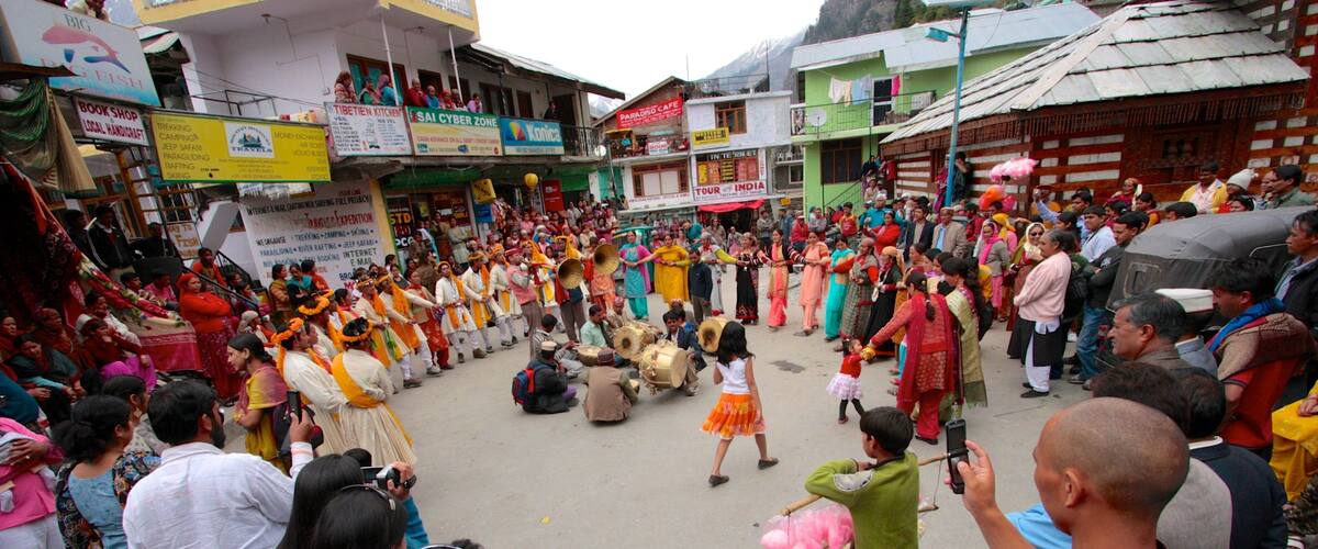 A traditional dance performance in a market square with colorful attire and drums.