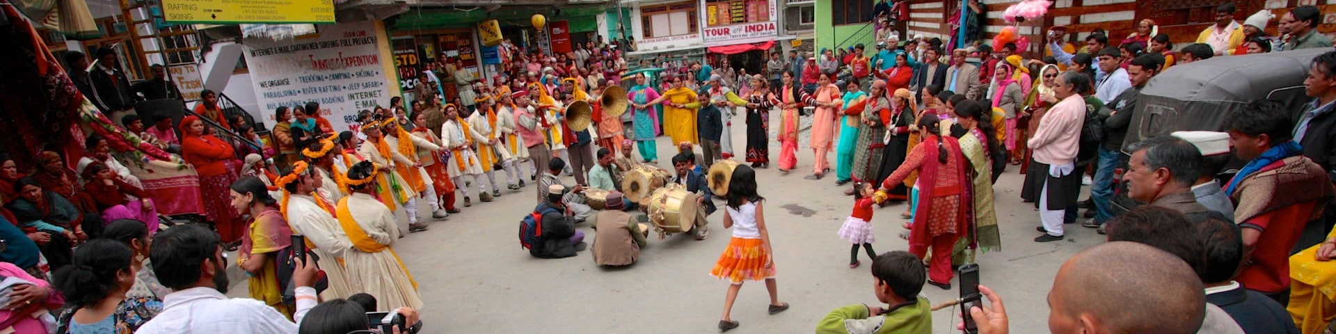 A traditional dance performance in a market square with colorful attire and drums.