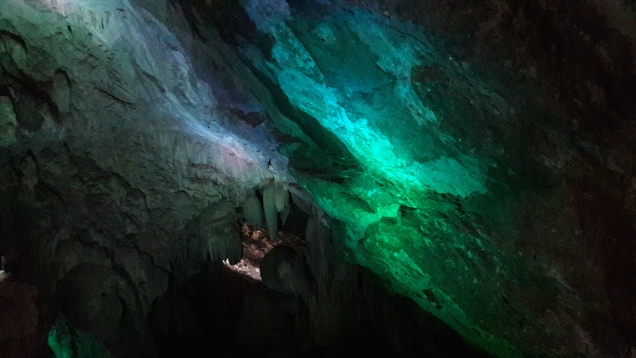 Une grotte éclairée de couleurs vertes et bleues.