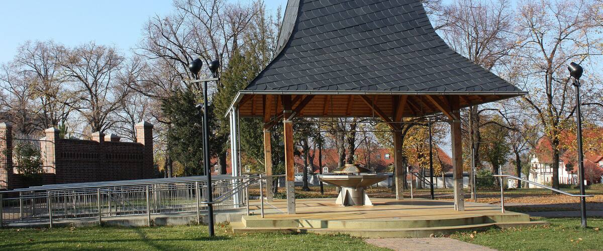 A gazebo with a unique conical roof in a park.