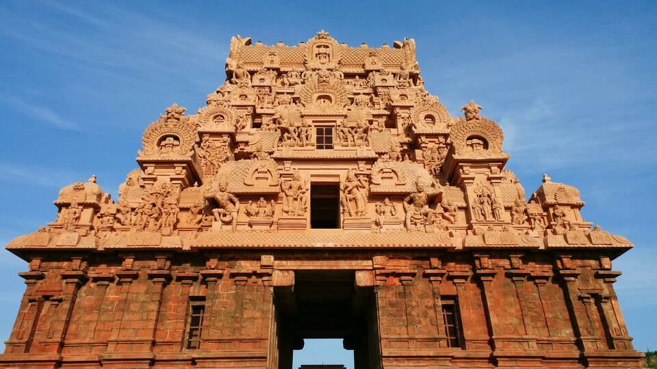 A detailed sandstone temple with intricate carvings and a central doorway.