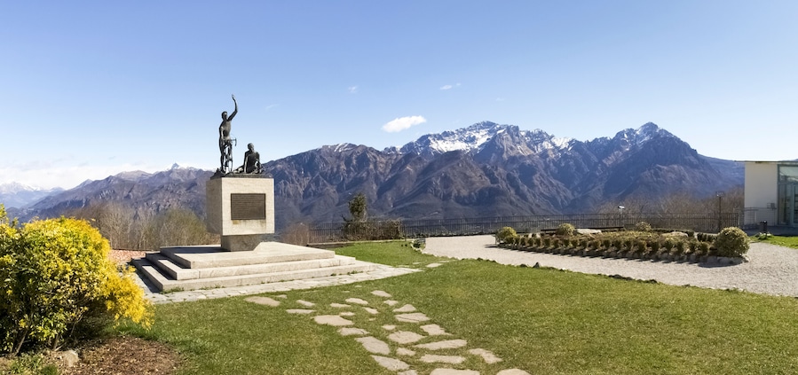 A statue on a pedestal with a mountainous backdrop.