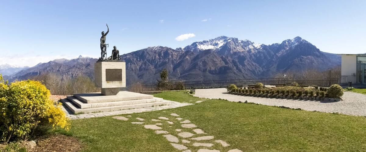 A statue on a pedestal with a mountainous backdrop.
