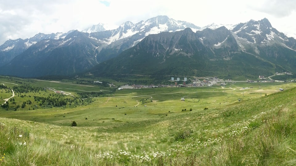 A mountainous landscape with a valley, a winding road, and a small settlement.