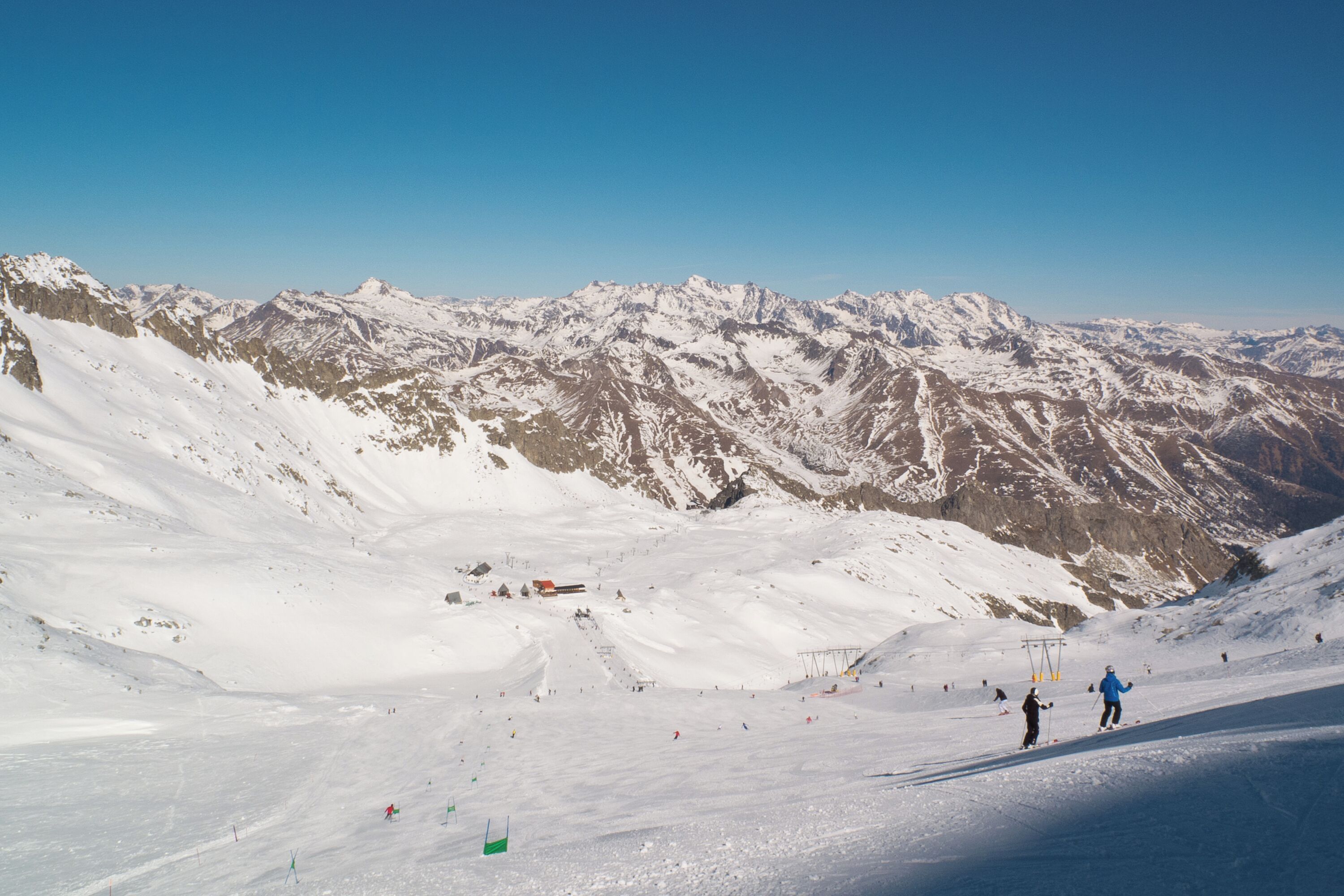 A snow-covered mountain landscape with ski slopes and a clear blue sky.