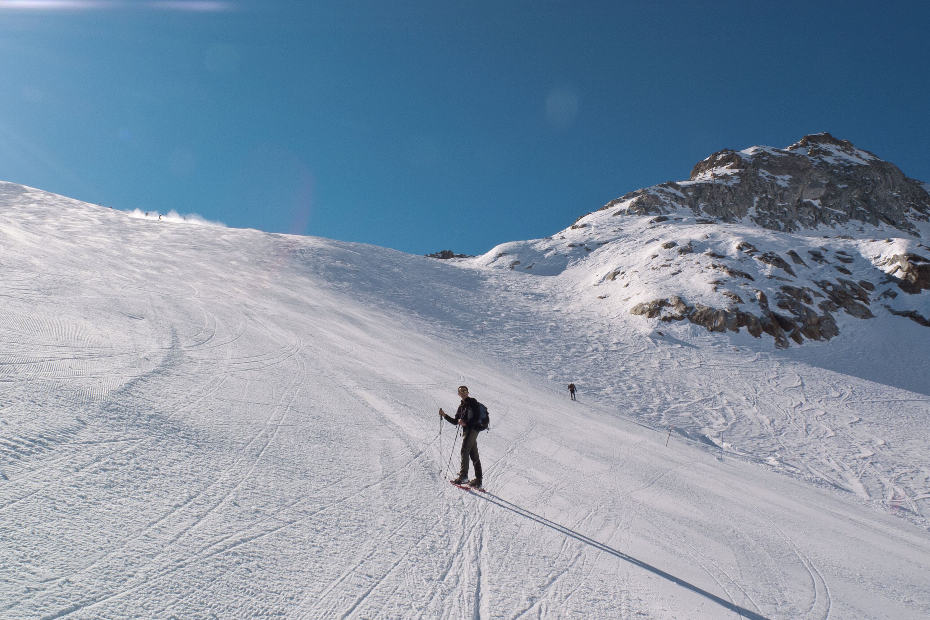A skier on a snowy slope with a mountain in the background.