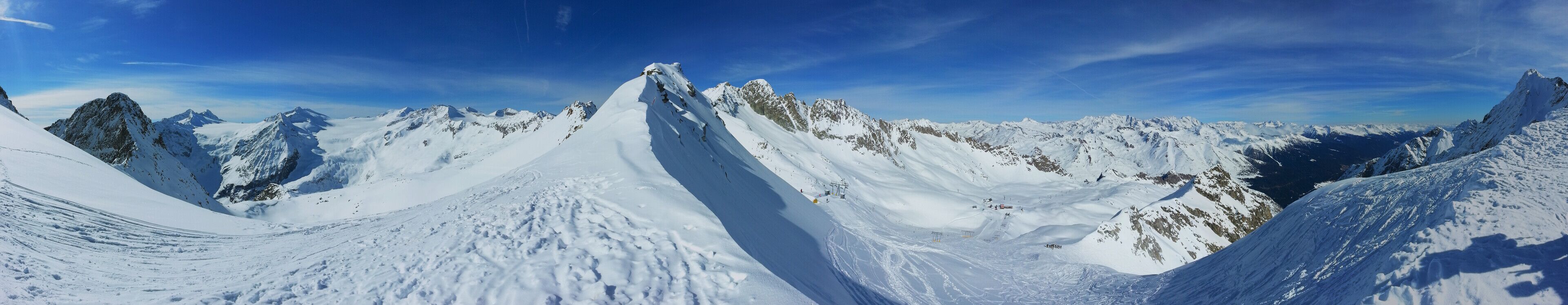 A snow-covered mountain range with sharp peaks and a clear blue sky.