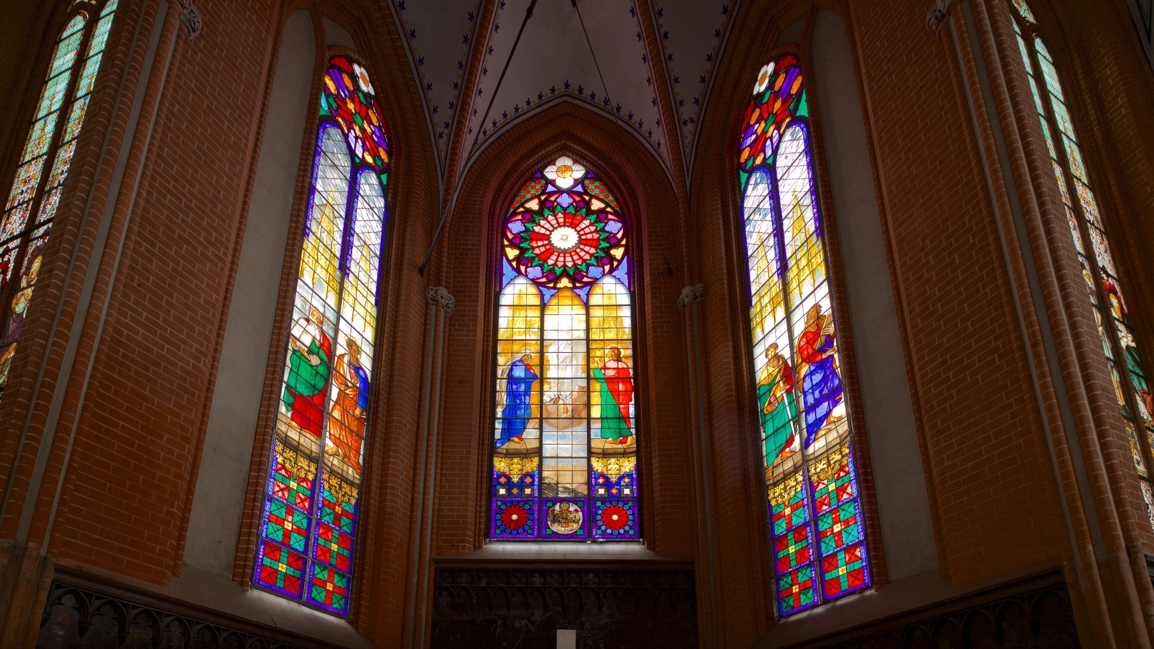 Interior de una iglesia con tres grandes vitrales.