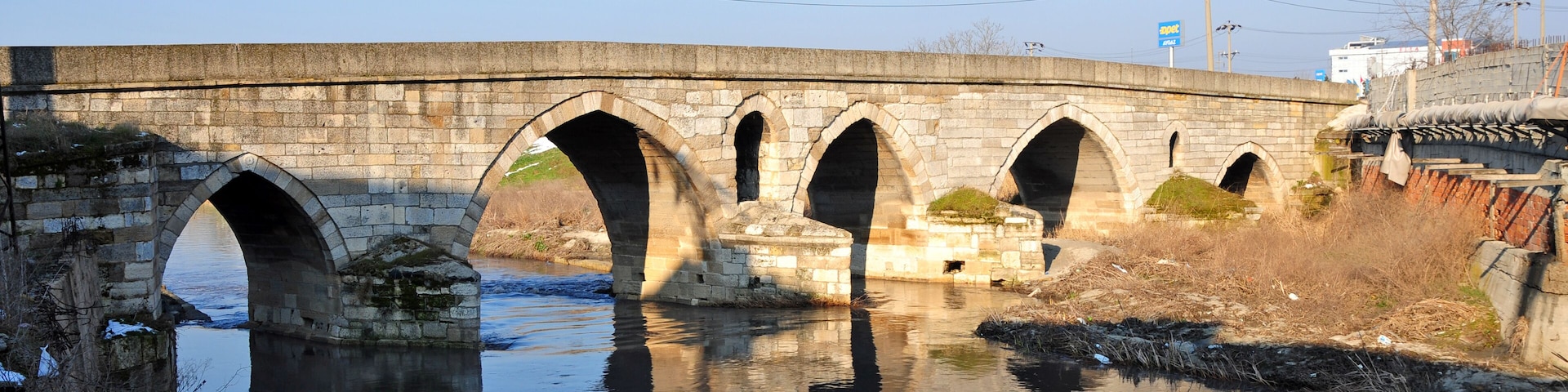 A stone bridge with multiple arches over a calm river.
