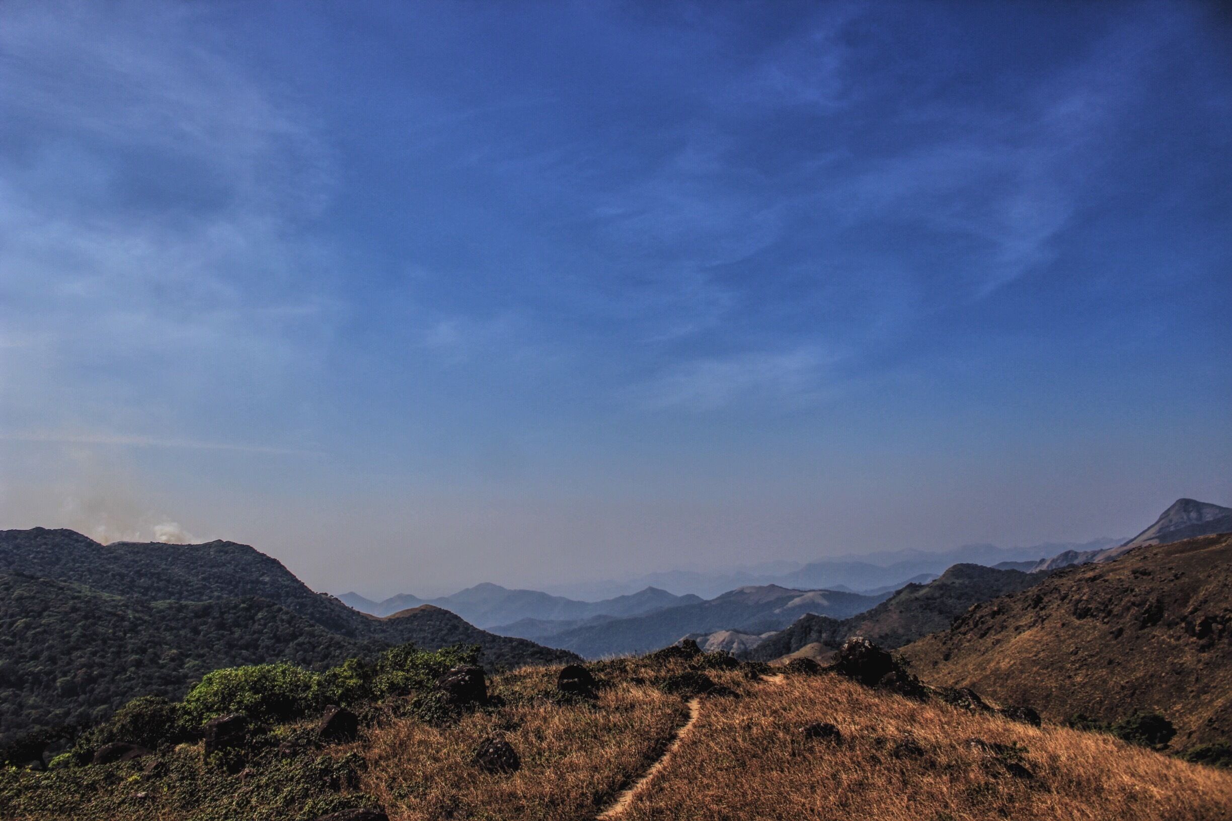 A mountainous landscape with a clear sky and a dirt path leading through the terrain.