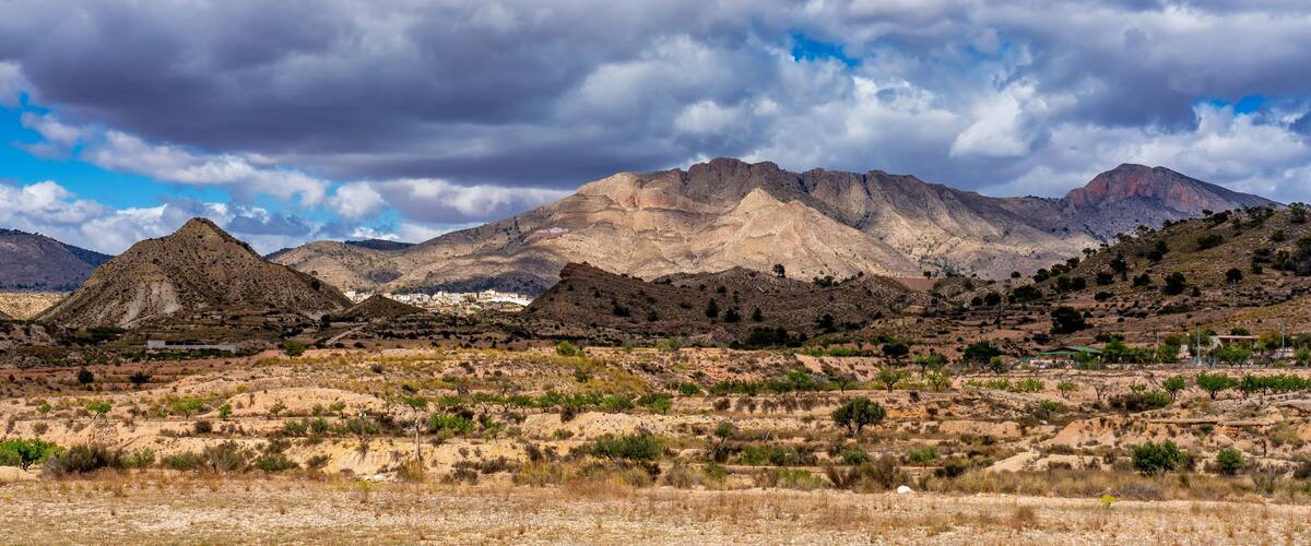 A mountainous landscape with sparse vegetation and a small settlement in the valley.