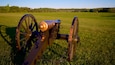A cannon in a grassy field with a clear sky.