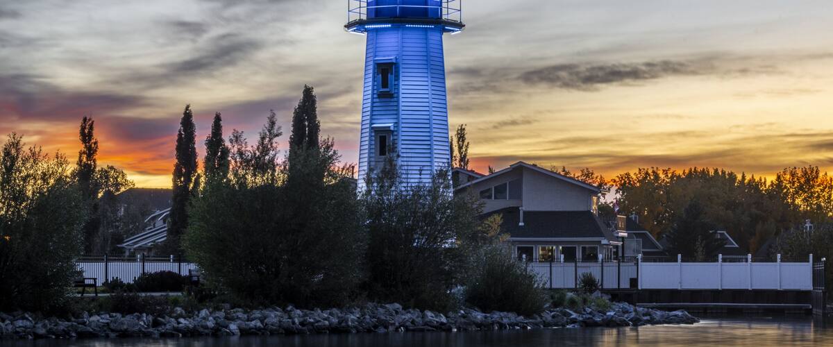 Un faro junto a un lago tranquilo al atardecer, con un cielo de ocaso.