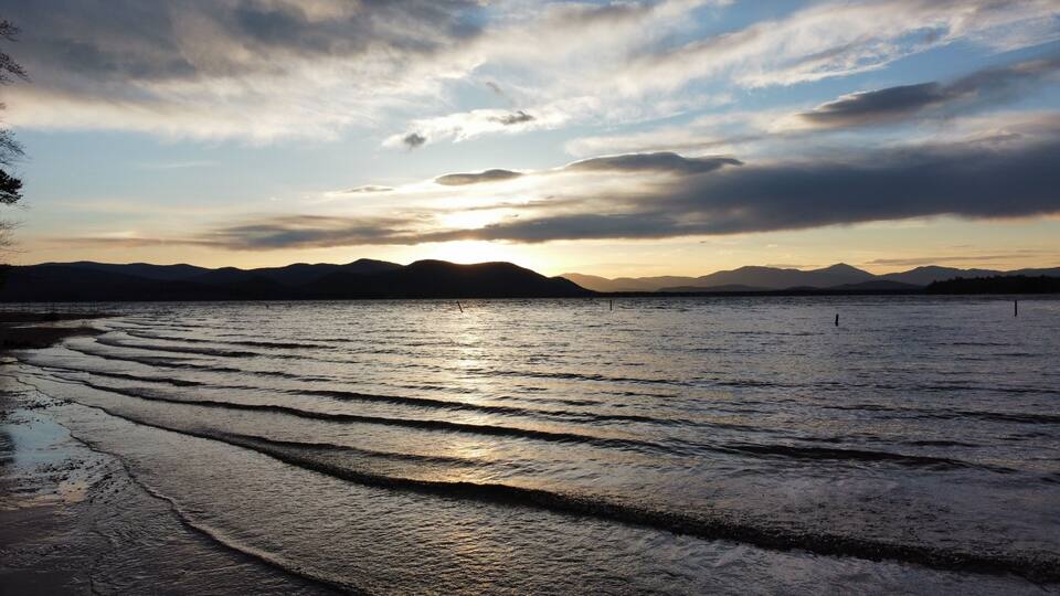 A sunset over a calm lake with mountains in the background.