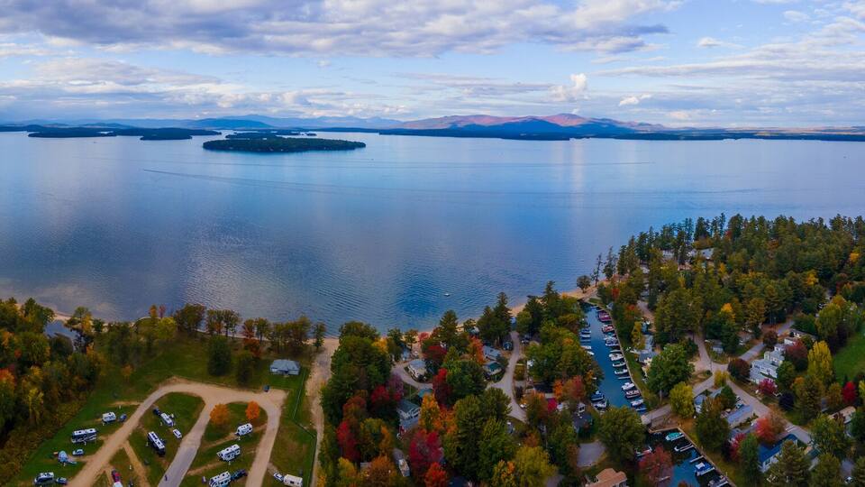 A lake surrounded by forested hills, a road, and a marina with boats.