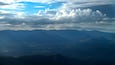 A mountainous landscape with a clear sky and scattered clouds.