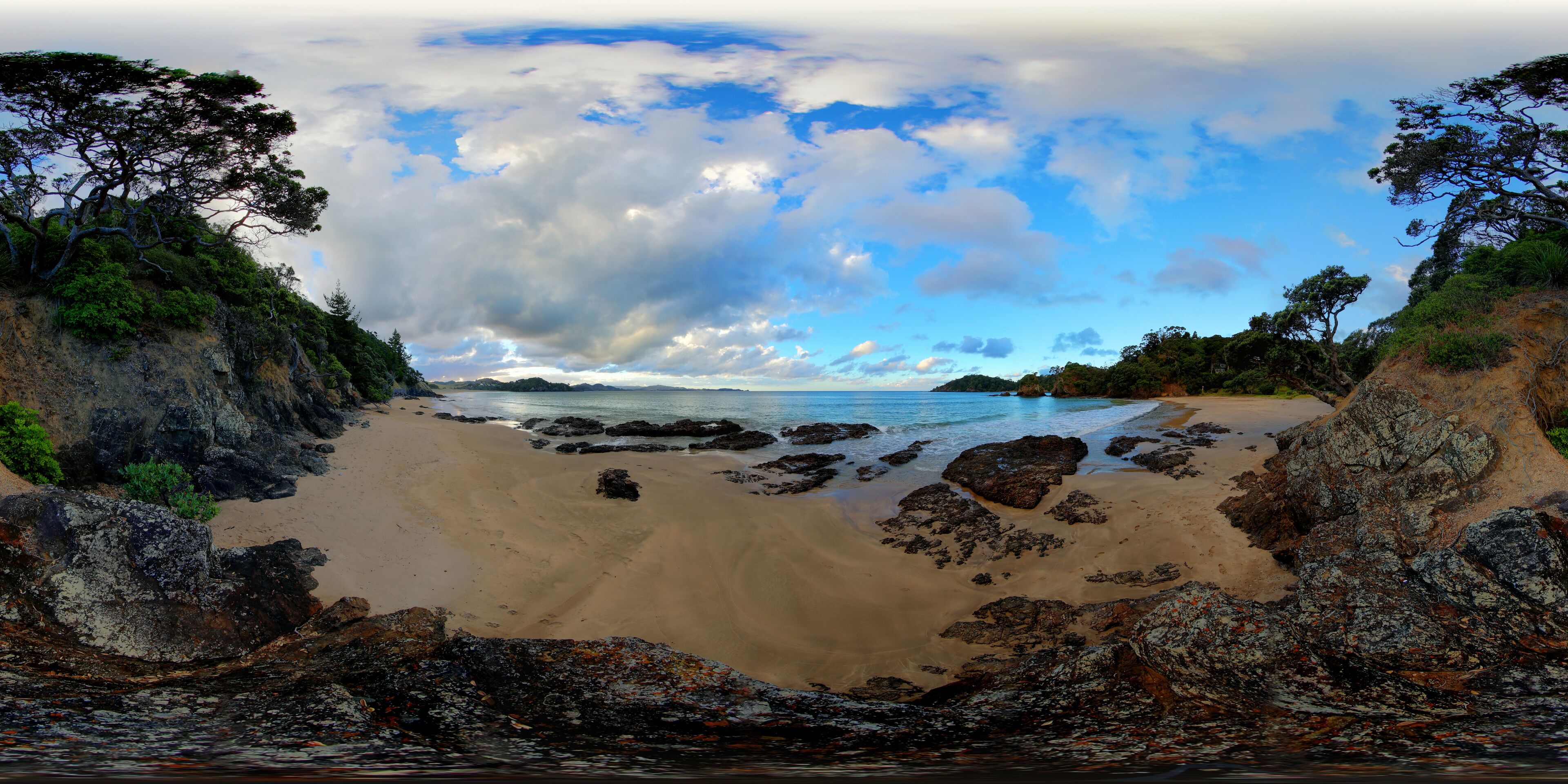 Una playa con afloramientos rocosos y cielo despejado.