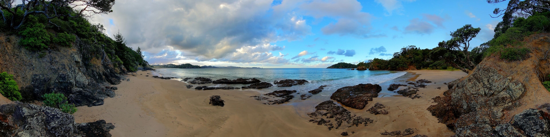 Una playa con afloramientos rocosos y cielo despejado.