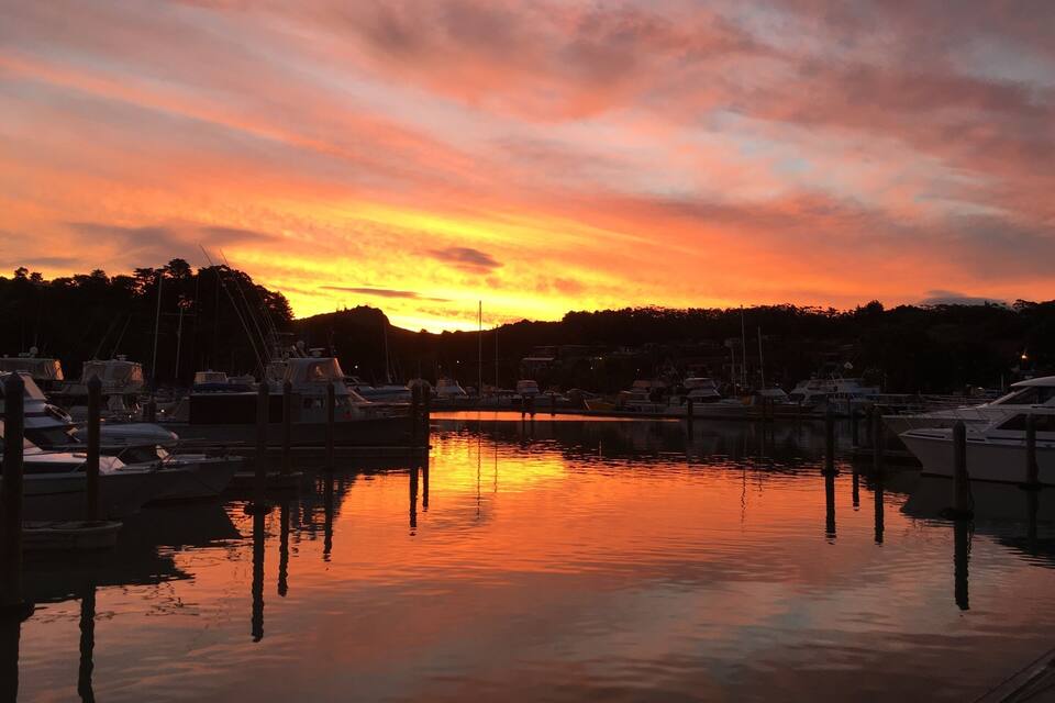 Een jachthaven bij zonsondergang met aan wal liggende boten en een weerspiegeling in het water.