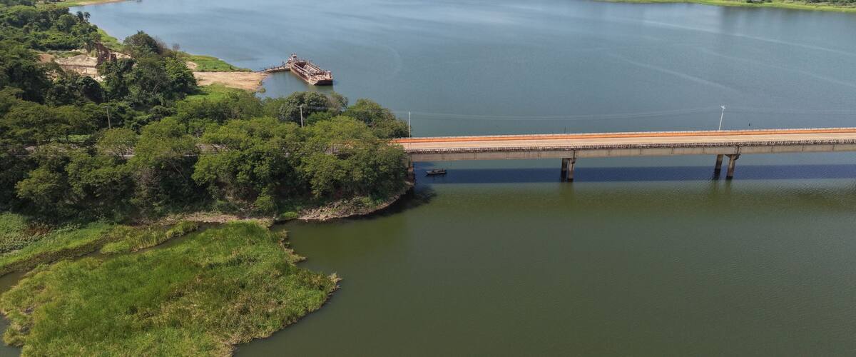 A river with a bridge, lush greenery, and a distant shoreline.