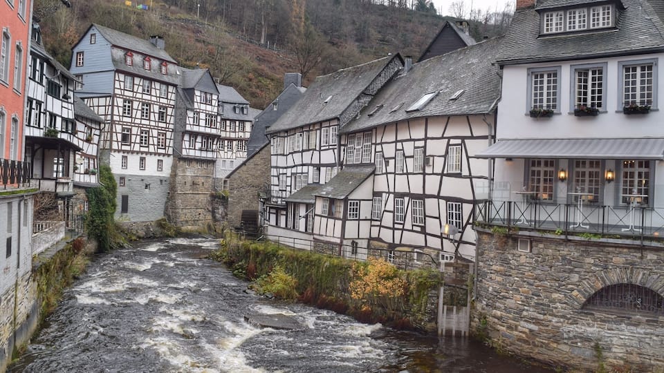 A river flowing through a town with traditional half-timbered houses.