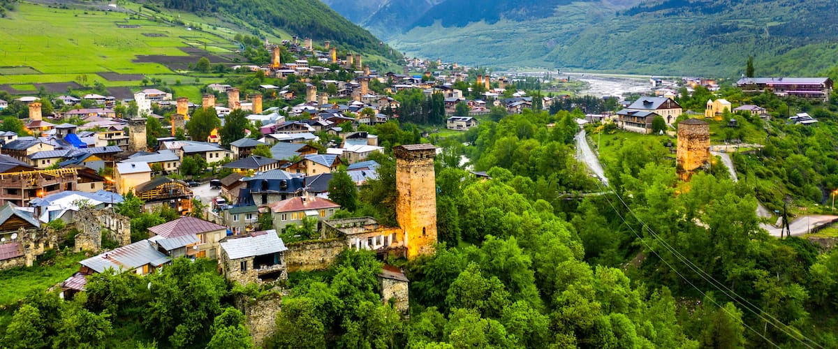 A mountainous village with historic buildings and a river.