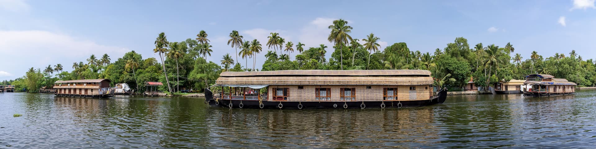 Panoramic river view and traditional house boat in Kerala's Backwaters, India.