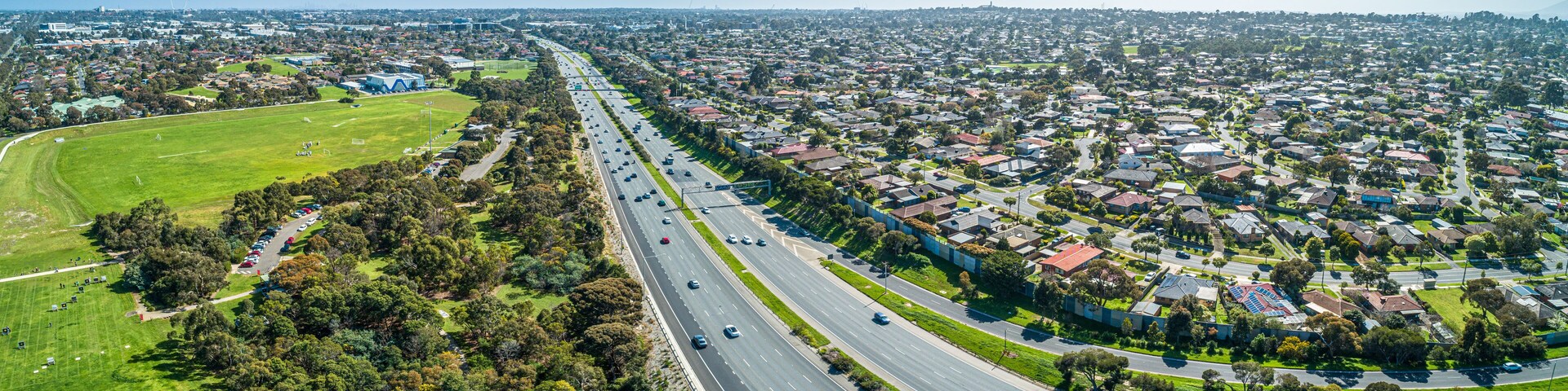 Aerial panorama of highway passing through suburban area on a sunny day in Melbourne, Australia