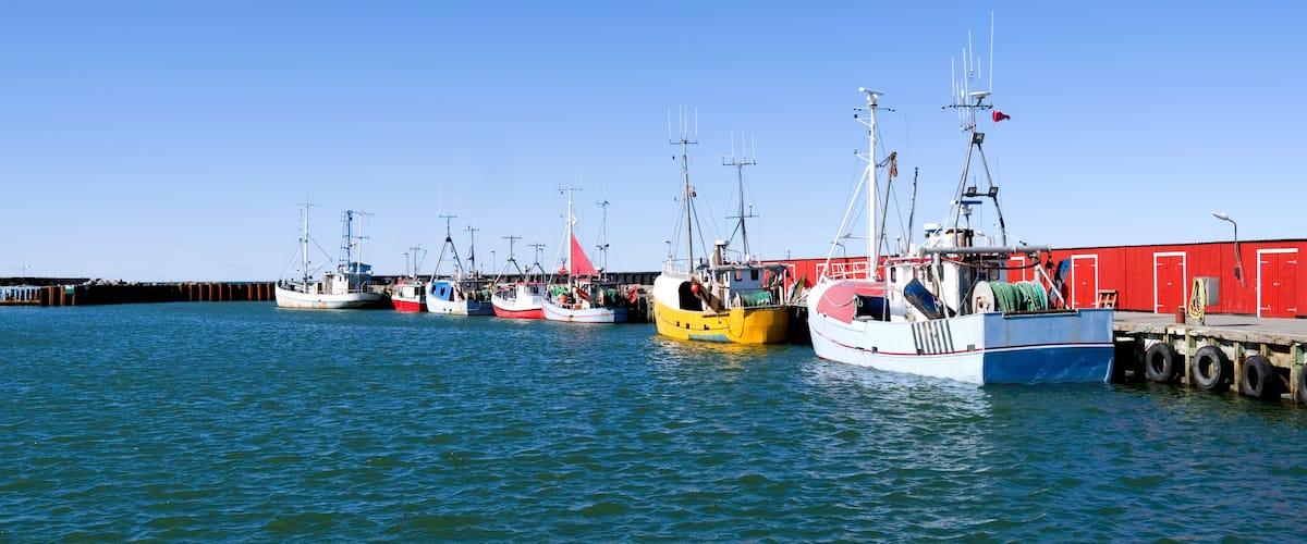 Laesoe / Denmark: Fishing cutters moored in a row at the pier in the small fishing port of Oesterby Havn in April