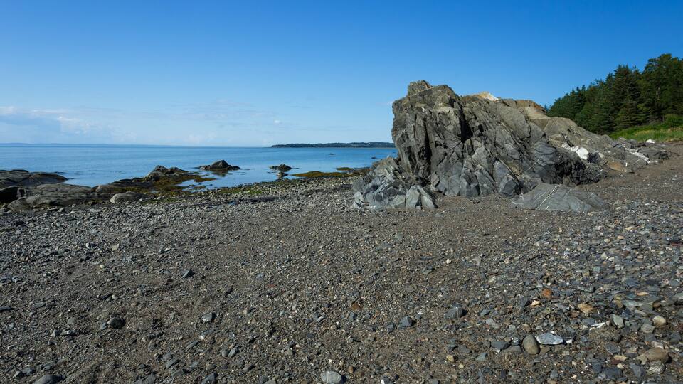 A rocky shoreline with a prominent rock formation and calm sea.