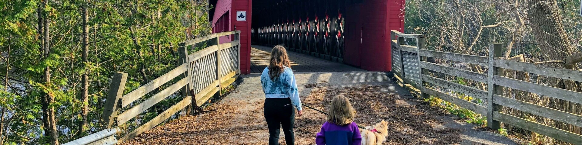 A red covered bridge labeled 'Wakefield 1997' with a woman and a child walking towards it.