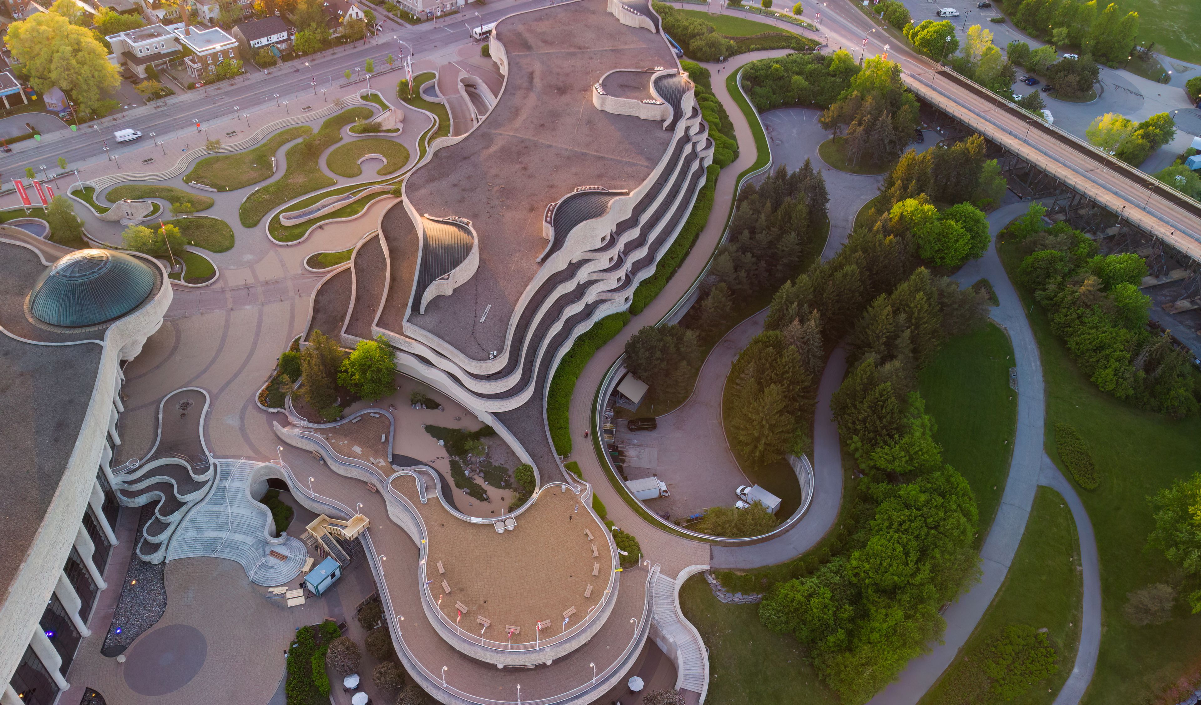 Vista aérea de un parque con senderos serpenteantes, una plaza circular central y zonas verdes circundantes.