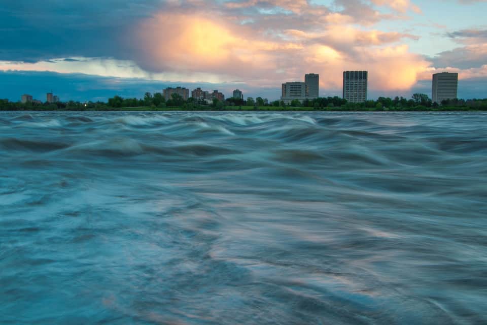 Une rivière avec la silhouette d’une ville en arrière-plan.
