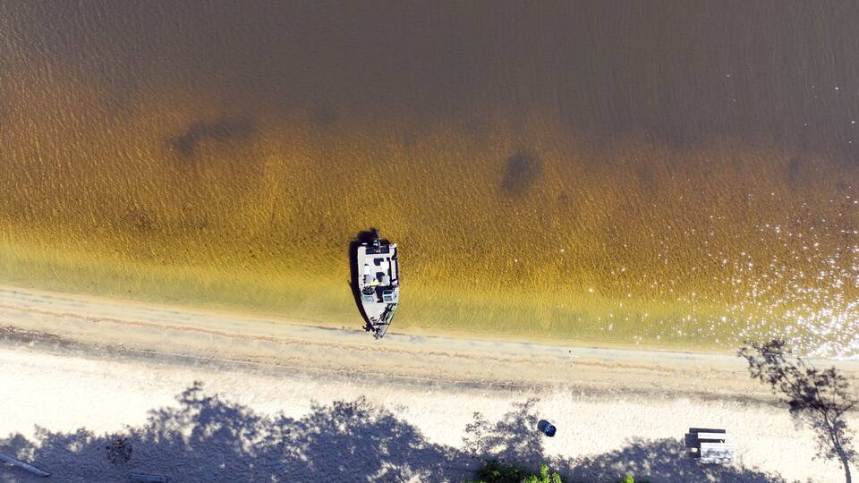Small boat moored on a white sand beach on the Ottawa River on a sunny day