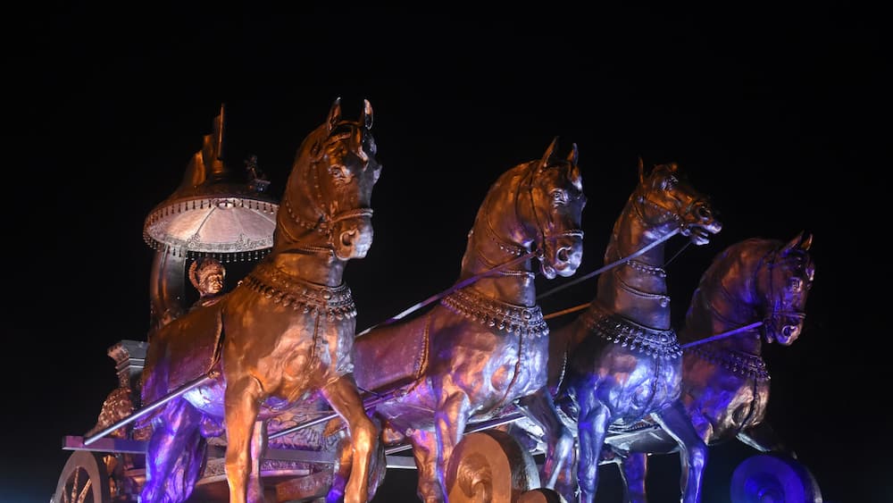 "Illuminated Bronze Chariot Statue of Krishna and Arjuna at Night in Kurukshetra, Haryana, India"