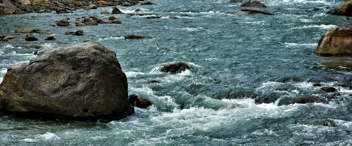 A river with rocks and a bridge.