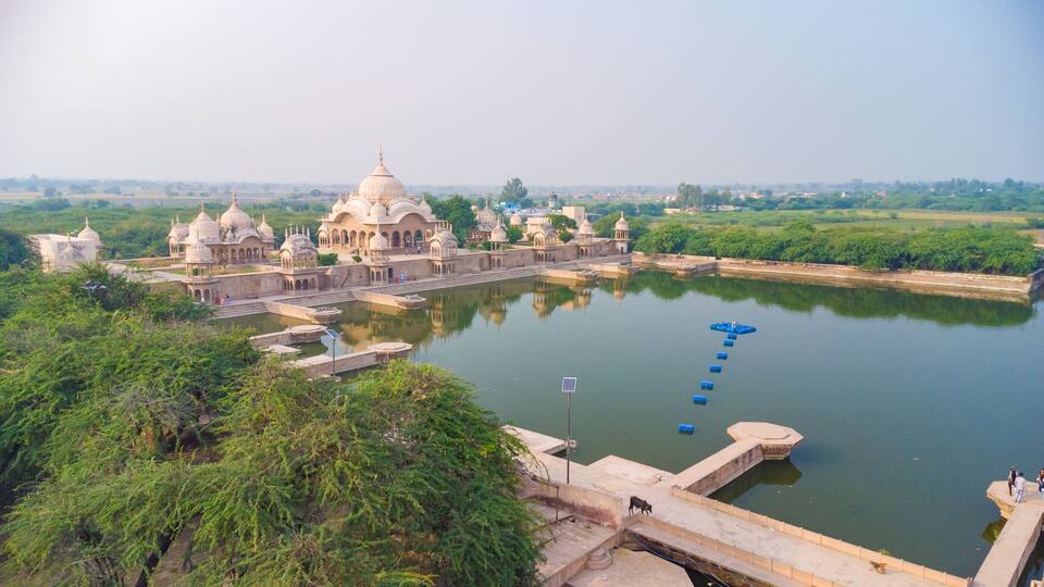 A historic palace complex with domed structures and a large water body.