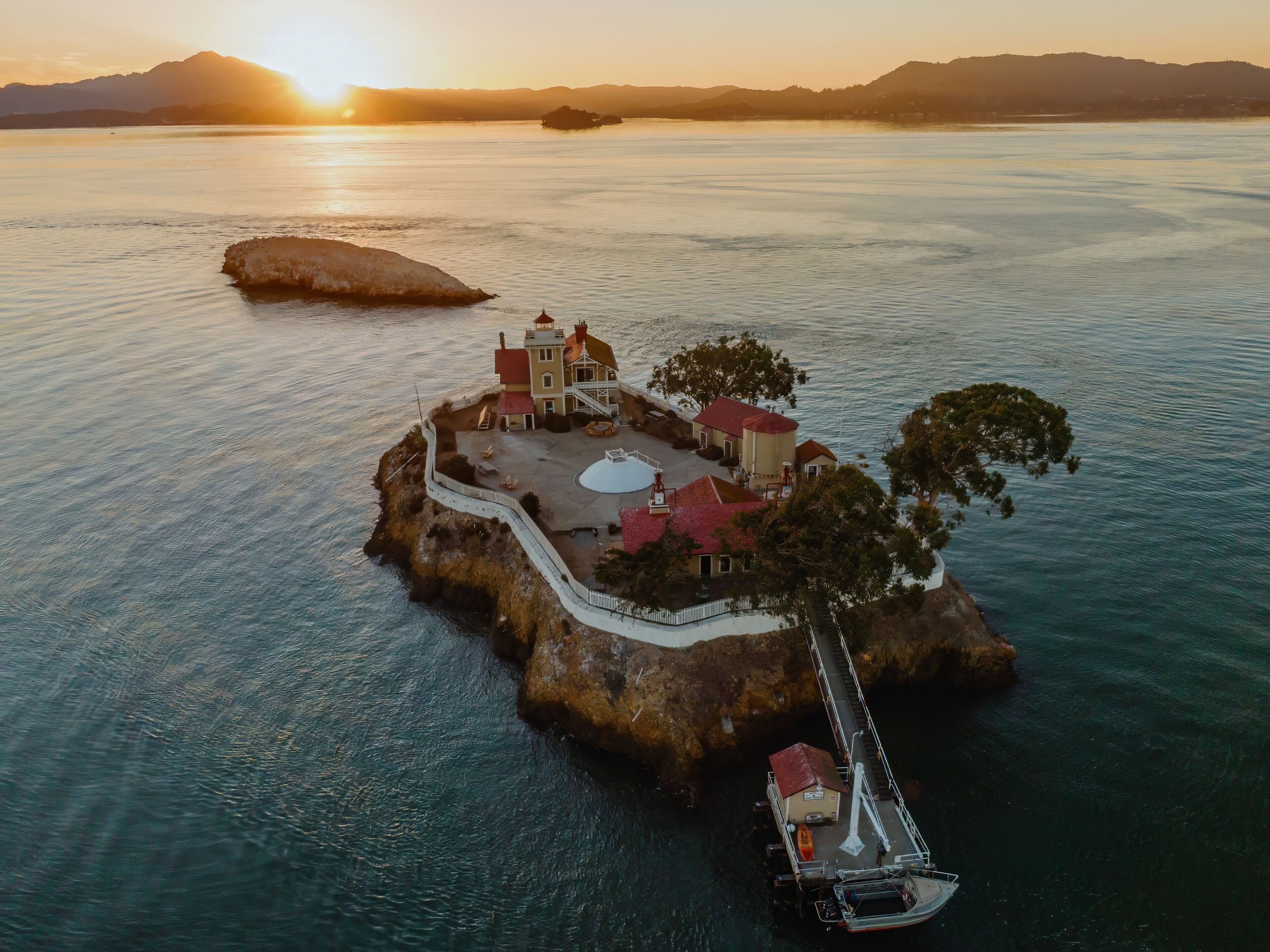 An aerial view of the Brothers Island Lighthouse, a historic landmark in Richmond, California, USA. The lighthouse stands on a rocky island, surrounded by the tranquil waters of San Pablo Bay.