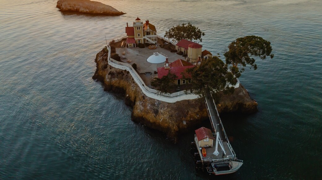 An aerial view of the Brothers Island Lighthouse, a historic landmark in Richmond, California, USA. The lighthouse stands on a rocky island, surrounded by the tranquil waters of San Pablo Bay.