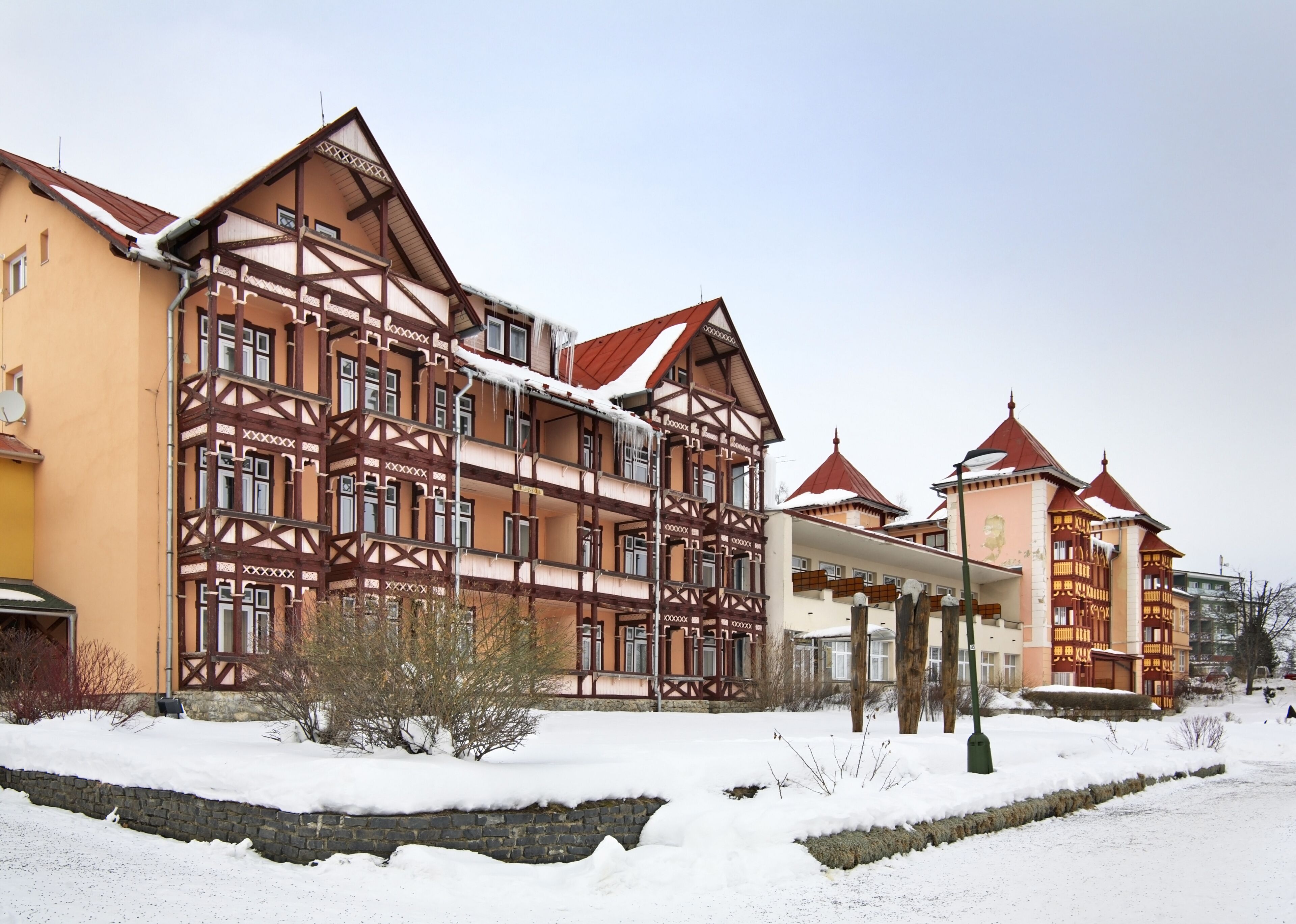 A traditional multi-story building with exposed wooden beams and red-tiled roofs, surrounded by snow.