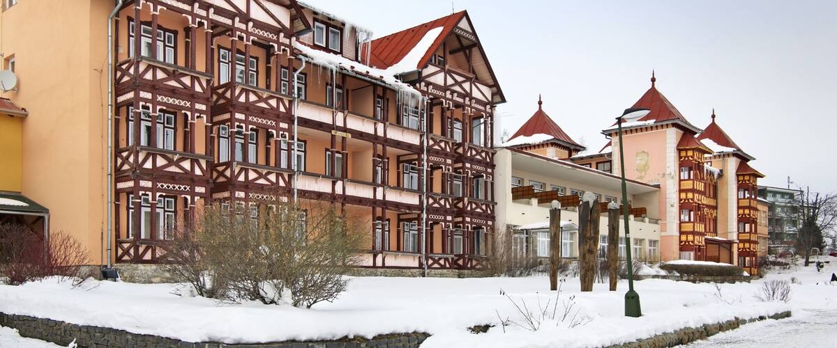 A traditional multi-story building with exposed wooden beams and red-tiled roofs, surrounded by snow.