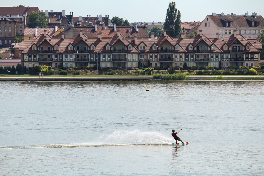 a boy riding a kiteboard against a background of picturesque houses in Ostroda, Poland; Shutterstock ID 518280943