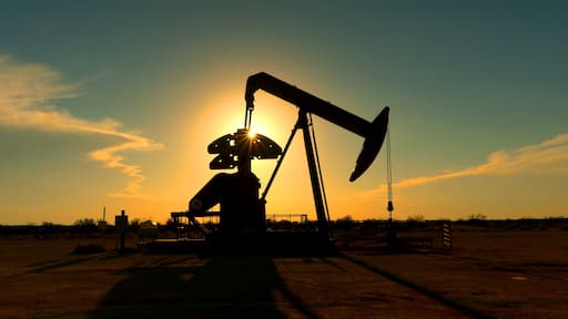 Industrial jack pump platform pumping crude oil over sunset sun