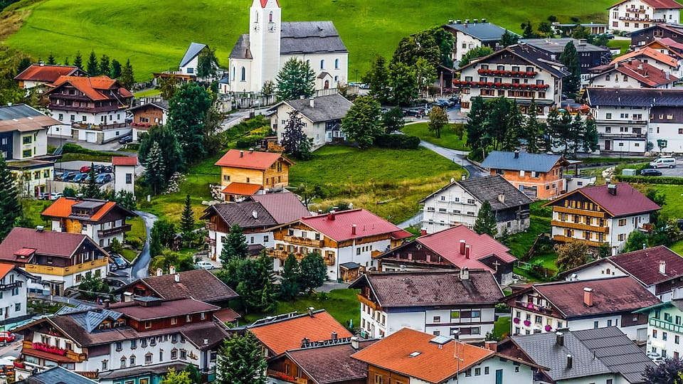 A village with a church, houses, and a green valley.