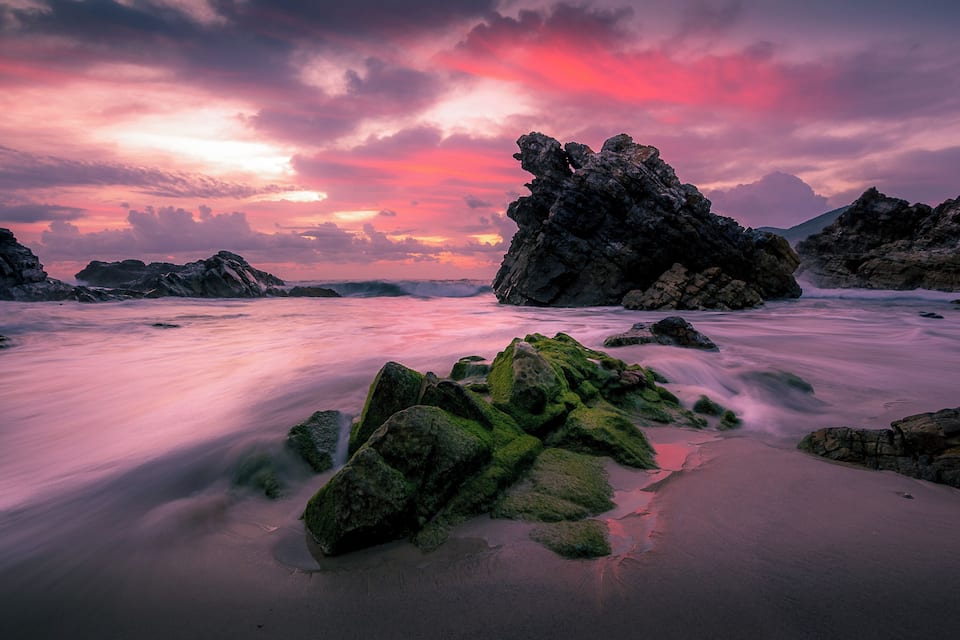 A rocky shoreline with a sunset sky.