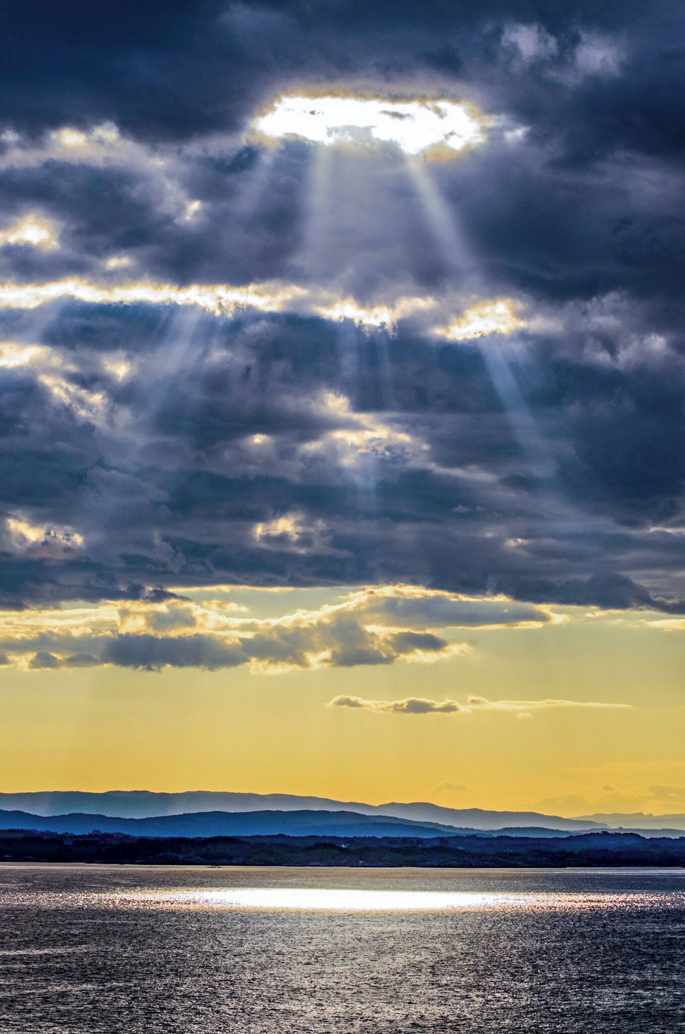 Sun breaks through a crack in the cloud of the Norwegian coastline.